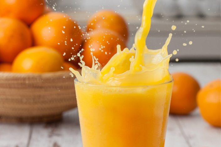 Orange juice being poured in a glass with splash.